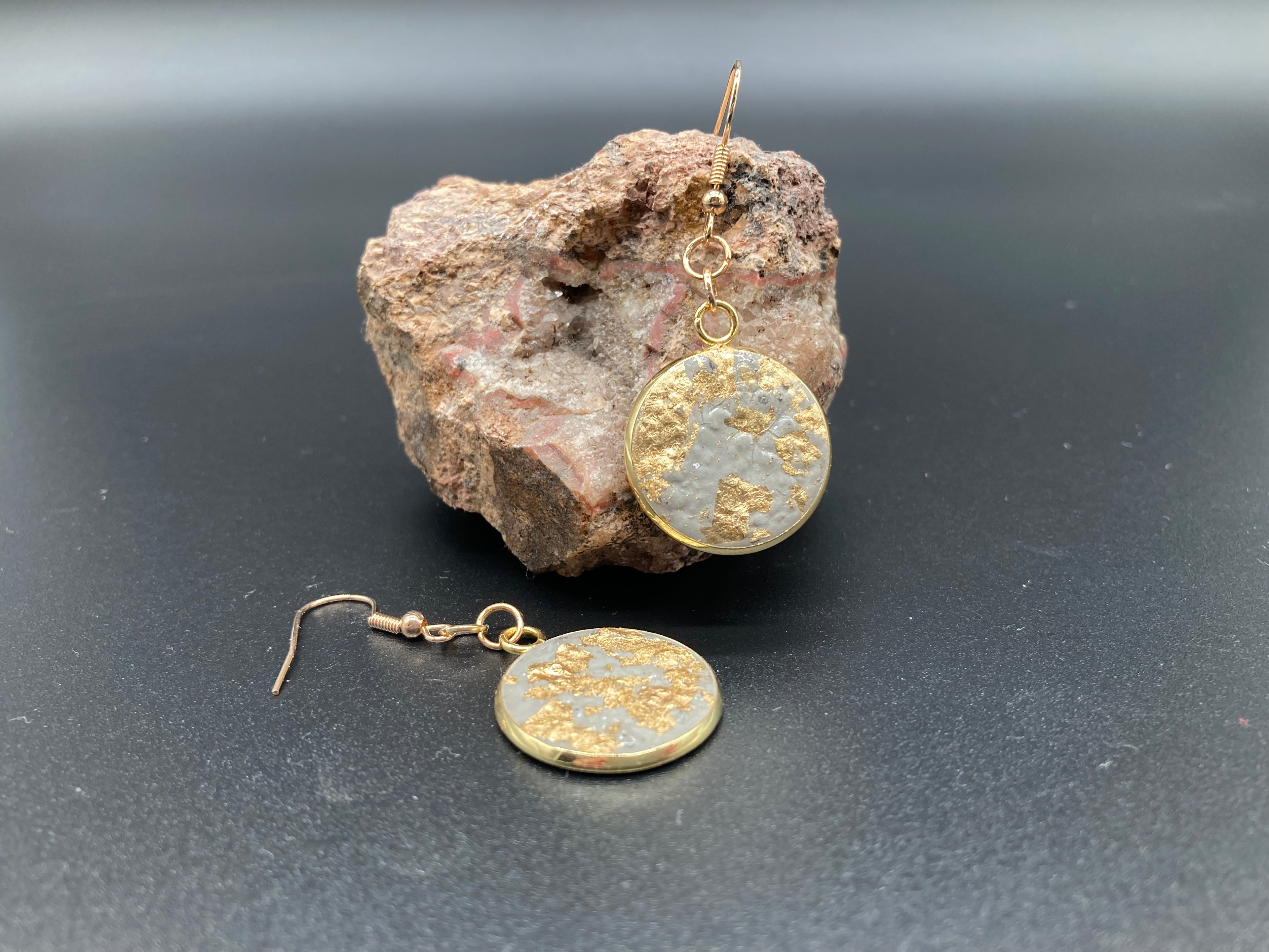 Runde Betonohrringe hängend in goldener Fassung mit Applikationen Produktfoto