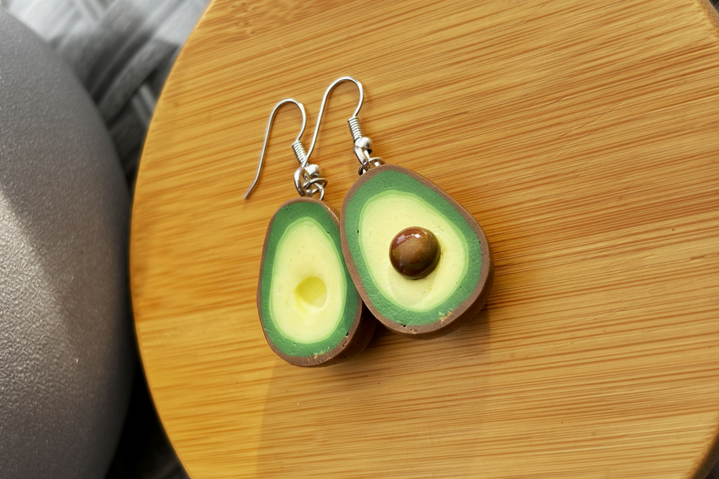 Handgefertigte Avocado Ohrringe Polymer Clay mit braunem Kern auf Holzuntergrund